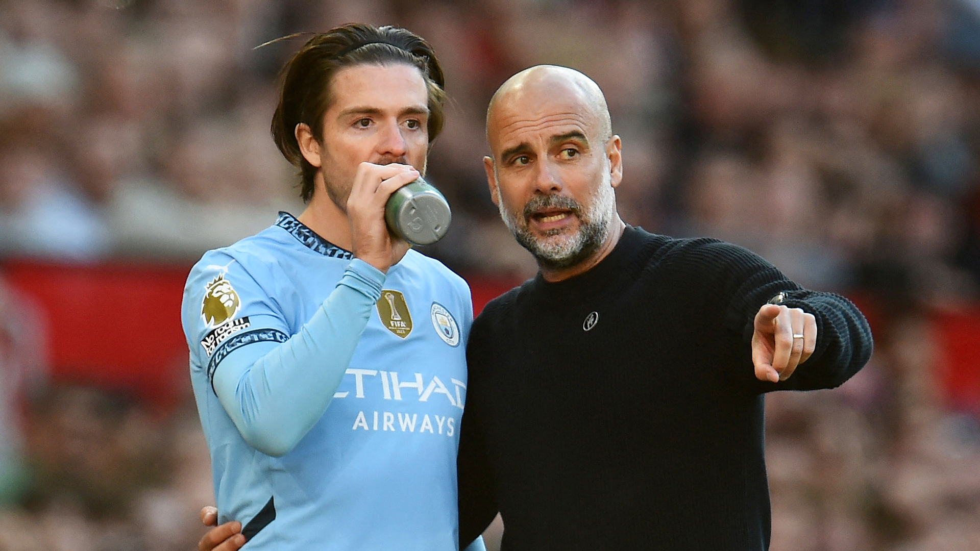 Pep Guardiola y Jack Grealish platican durante un partido del Manchester City.